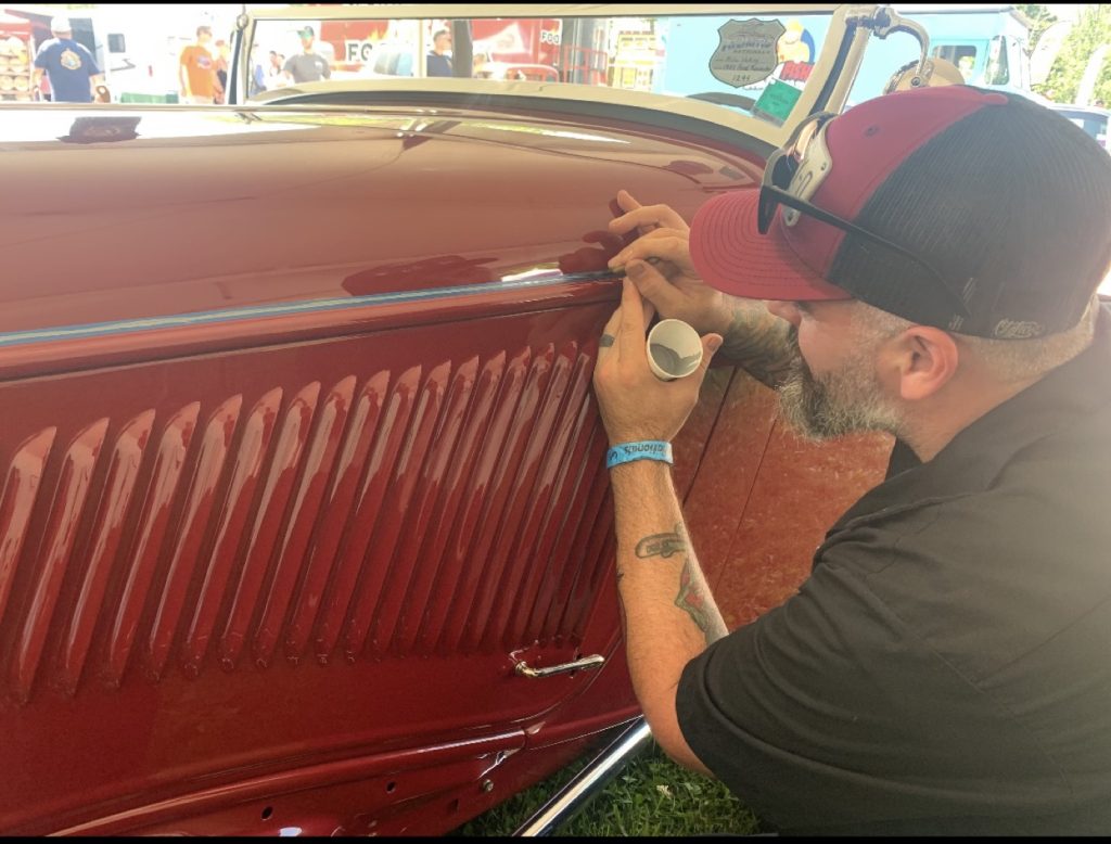 Hand pinstriping on a red vehicle door